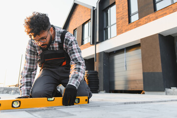 Construction worker laying paving using spirit level