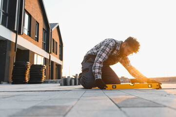 Worker using spirit level installing paving stones