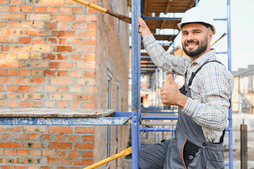Smiling construction worker giving thumbs up on scaffolding