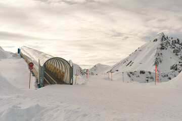 Covered moving walkway ascending a snowy mountain slope