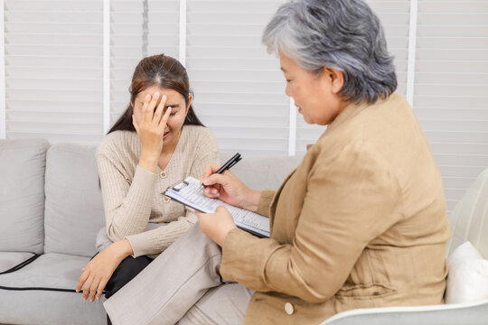 Therapy, counseling, senior psychologist, consultation, mental health, young woman stressed, using hand gesture to explain anxiety during session with counselor, reflecting workplace conflict struggle