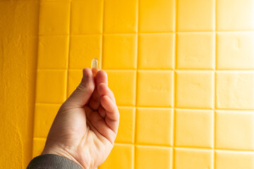 Hand holding softgel supplement pill for daily health