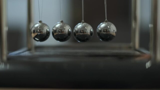 Newton's cradle desk toy, perpetual motion and physics conservation of momentum concept