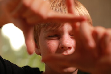 Young boy framing vision with hands, focusing on future
