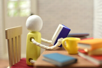 読書をする木製人形の写真　積まれた本　趣味の時間　勉強　ミニチュア
