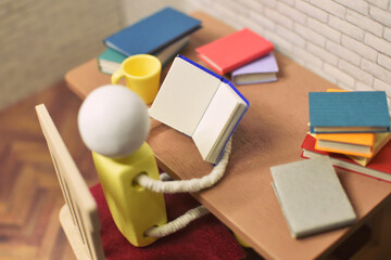 読書をする木製人形の写真　積まれた本　趣味の時間　勉強　ミニチュア