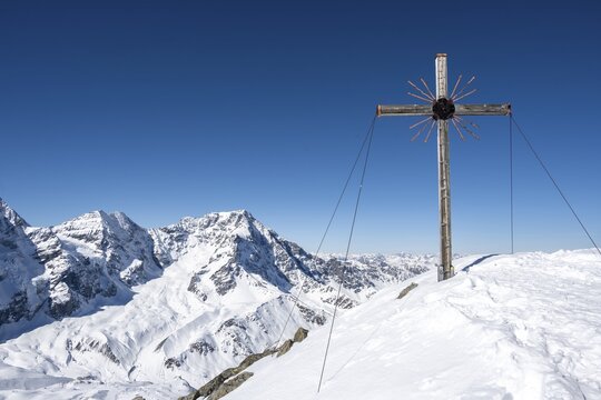 Snow-covered mountain landscape, summit cross of the Madritschspitze, Ortler Alps, Vinschgau Valley, Italy - Powered by Adobe