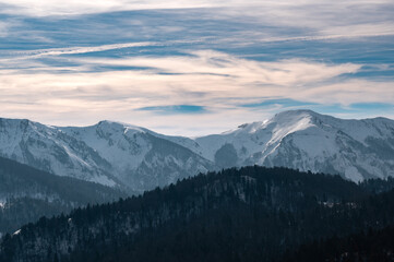 Fototapeta premium Snowcapped mountains with winter forest under blue sky
