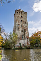 Medieval brick residential tower of Castle Den Ham standing tall surrounded by a moat and autumn trees in the Dutch countryside.