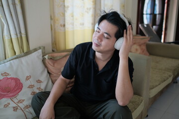 Obraz premium A man wearing headphones is sitting on a couch