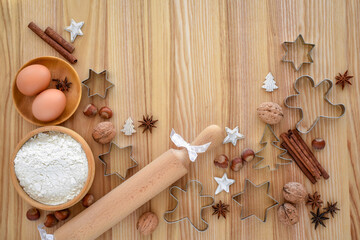 Holiday baking setup with flour, eggs, and festive cookie cutters on a wooden table
