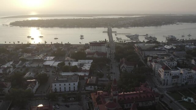 Aerial view of Bridge of Lions and boats over calm waters, with buildings lining the shore contrasting with the bright sky, St. Augustine, Florida, United States.