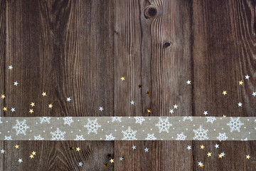 Festive Christmas background. Decorative ribbon and stars on dark wooden background.