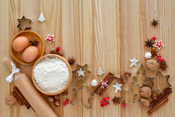 Holiday baking setup with flour, eggs, and festive cookie cutters on a wooden table