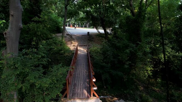 Aerial view of a wooden bridge stretching over a lush green landscape towards a paved path near Wishes Bridge, Varna, Bulgaria.