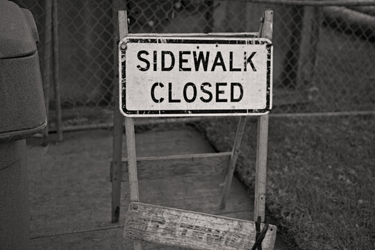 Weathered sidewalk closed sign marking a pedestrian restriction in Sunset Beach, California, highlighting urban infrastructure, safety, and everyday street maintenance.