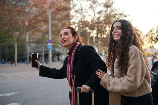Mother and daughter hailing a cab on city street