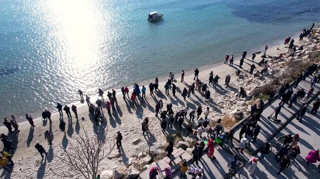 Aerial view of people gathering on a bright sandy beach next to the turquoise sea, creating a vibrant contrast, Varna, Varna, Bulgaria.