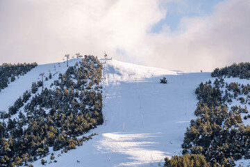 Snow covered mountain peak with ski run under winter sky