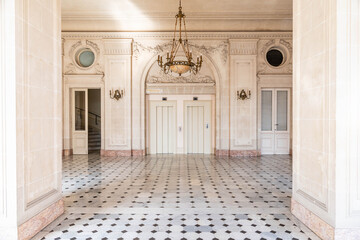 Fototapeta premium Elegant historic interior hall with marble columns, patterned floor and chandelier in classical palace