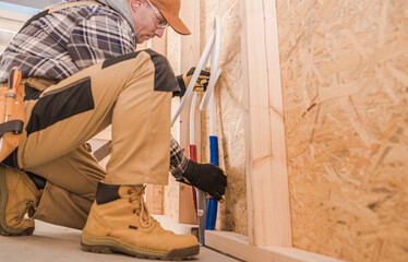 Worker Installs Pipes in a Wooden Structure During a Construction Project
