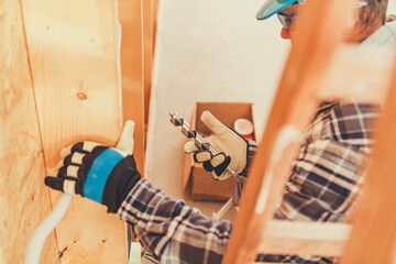 Worker Drills Wood in Construction Site During Day