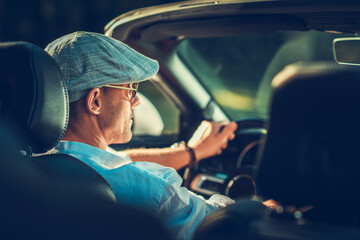 Man Driving Convertible Car With Cap on a Sunny Day in a Scenic Area