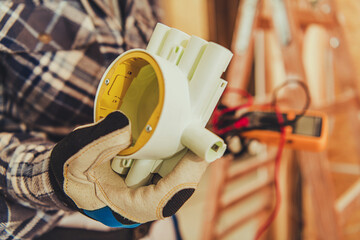 Electrician Holds Wiring Box During Home Renovation in Workshop