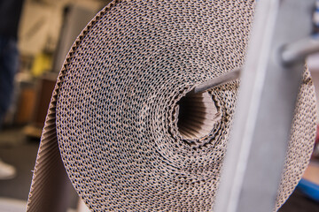 Roll of Brown Cardboard Placed on a Machine in a Workshop During Daytime