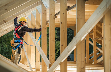 Worker Climbs Wooden Beams During Construction in a Building Site