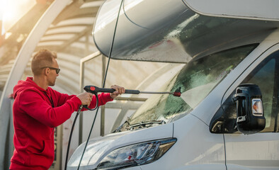 Person Washing a Camper Van With a Pressure Washer During Sunny Day