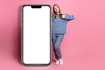 Young woman smiling confidently in casual striped sweater next to blank white board on vibrant pink background