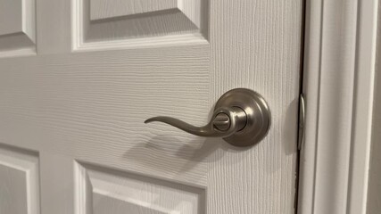 Female hand unlocks an interior door with a lever handle, showing a basic home access and daily routine action. Close up indoor shot with a clean background.