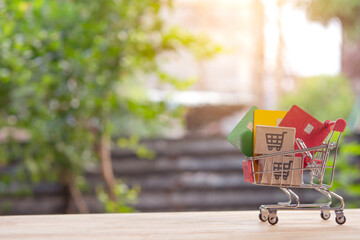 Mini shopping cart with cardboard boxes and credit card on wooden table