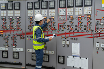 Electrical engineer adjusting control switches inside power facility, responding to system conditions to maintain balance, operational stability, and continuous electricity distribution 