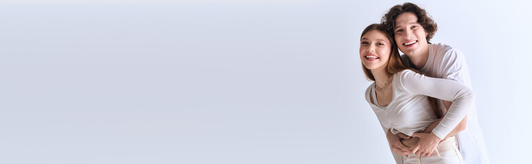 Joyful young couple sharing a cozy moment in a serene grey studio setting