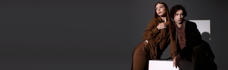 Stylish couple showcases modern fashion in a sleek grey studio setting