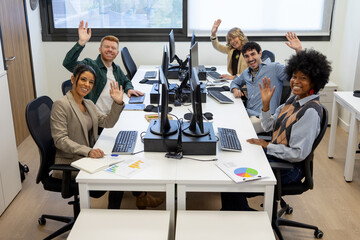 Diverse business team smiling and waving in office