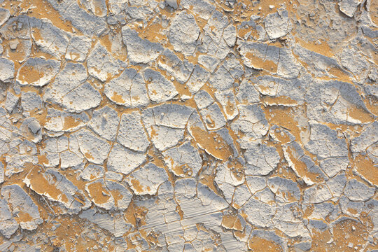 View of parched, cracked earth showing a stark contrast between the dry, pale surface and the warm, sandy soil beneath, Bateen Liwa, Abu Dhabi, United Arab Emirates.