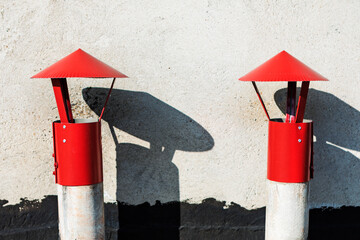 Red metal cone top chimney caps or rooftop ventilation caps, installed on top of concrete posts or pipes. Protect ventilation system from rain, snow, still allowing proper airflow and smoke exhaust