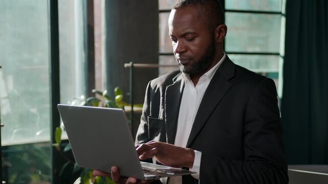 African American ethnic business man concentrated businessman typing laptop online software chatting in office middle-aged male entrepreneur in sunlight office indoors using computer programming job