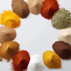 Different spices arranged in a circular pattern on a white surface for cooking purposes