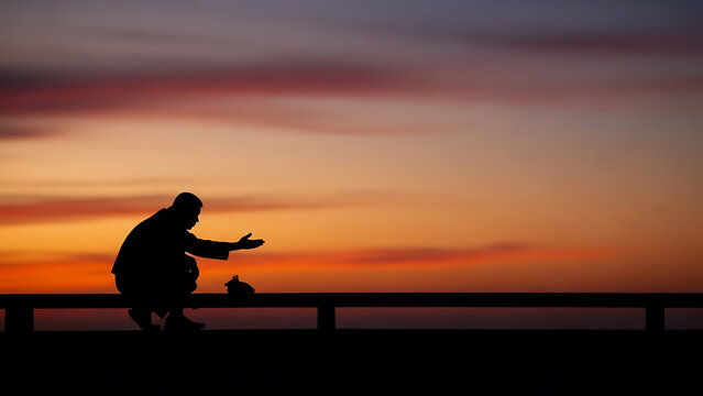 Silhouette of a person interacting with a small animal against a vibrant sunset sky