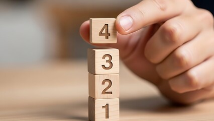Counting Down: Hand Placing Wooden Block with Number 4 on a Stack Representing Numbered Steps