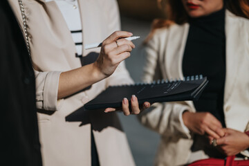 Fototapeta premium Two business professionals review a notebook and marker during a discussion. A close scene of a work meeting with focus on planning.