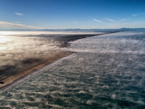 Aerial view of the mist rising above the waters, partially obscuring the land and the distant horizon, Hossegor, France.