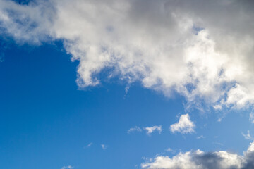 Photograph of white clouds floating gently over a clear blue sky, creating a calm and minimal natural background with a sense of openness and tranquility.