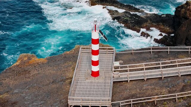 Farolim dos Fenais da Ajuda lighthouse on rocky promontory with foaming Atlantic ocean, Azores Islands. Aerial view