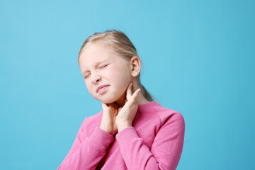 Little girl suffering from sore throat on light blue background. Cold symptom
