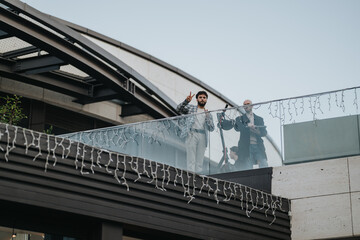 Obraz premium Two men on a rooftop terrace with string lights, glass railing, and modern architecture in the background.